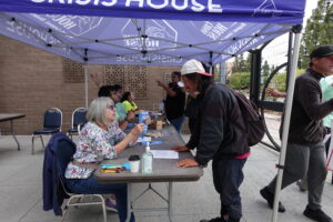 Person standing next to a Crisis House table being assisted