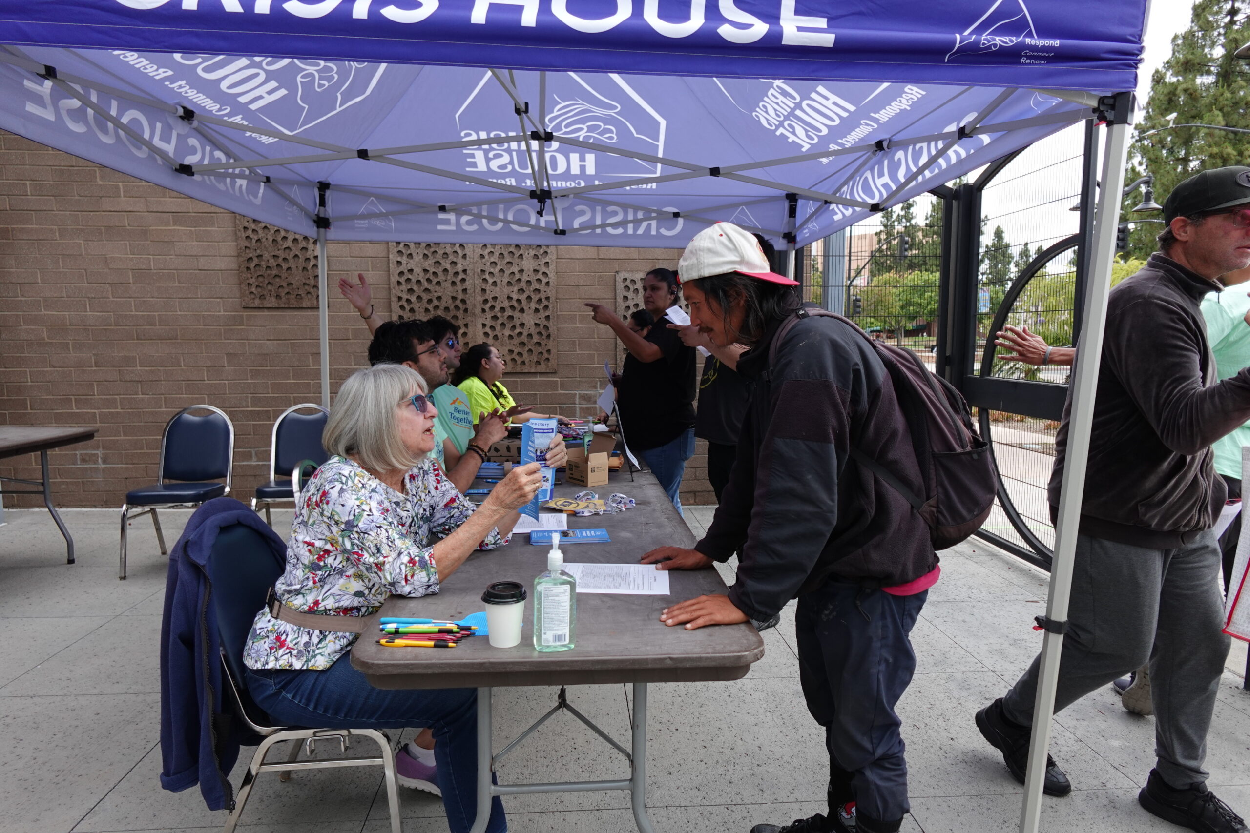 Person standing next to a Crisis House table being assisted